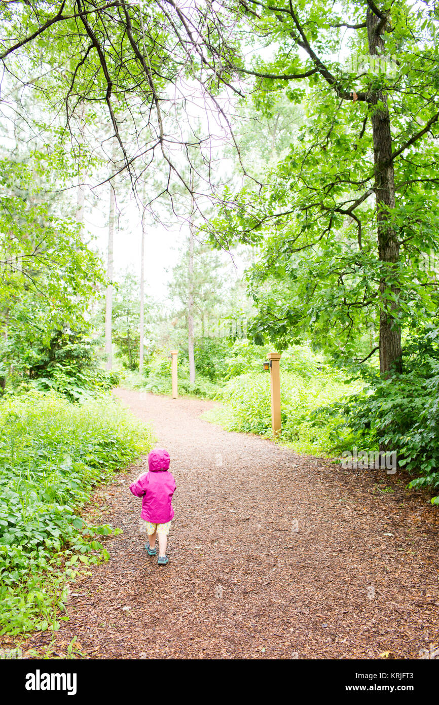 Caucasian girl walking on path in forest Stock Photo