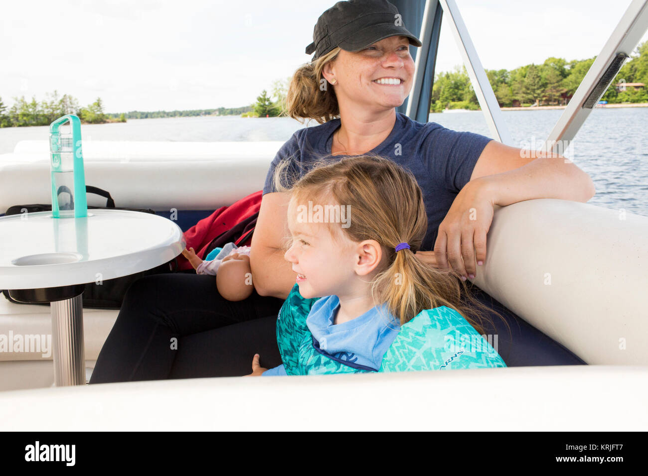 Smiling Caucasian mother and daughter relaxing on boat Stock Photo