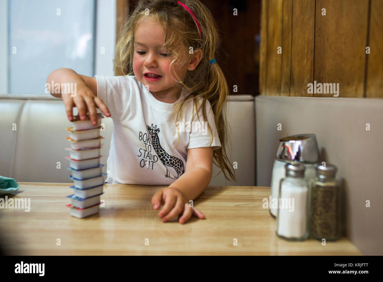 Smiling Caucasian girl stacking jelly containers in restaurant booth Stock Photo