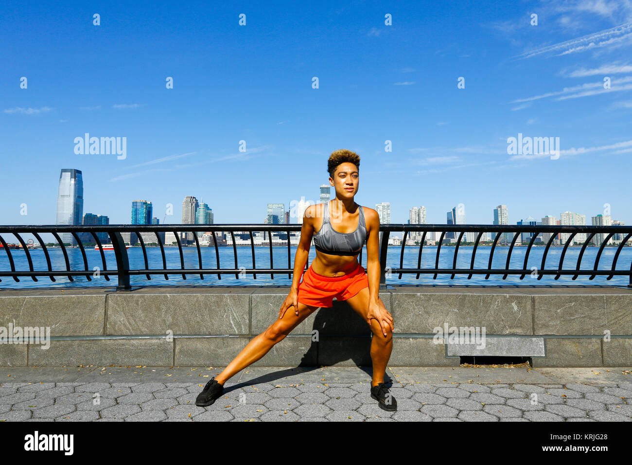 Mixed race woman stretching legs at waterfront Stock Photo