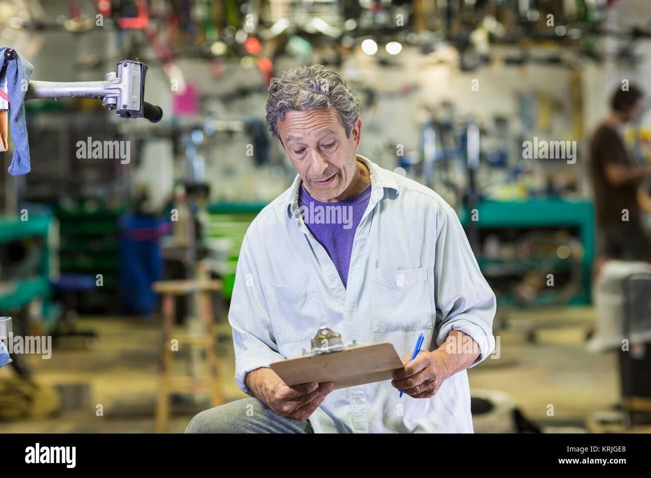 Caucasian man reading clipboard in bicycle shop Stock Photo