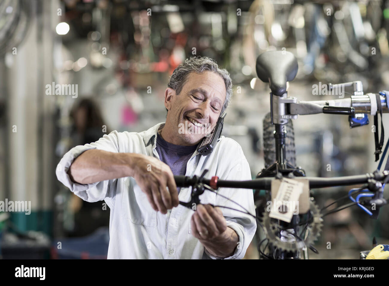 Caucasian man talking on telephone and repairing brakes on bicycle Stock Photo