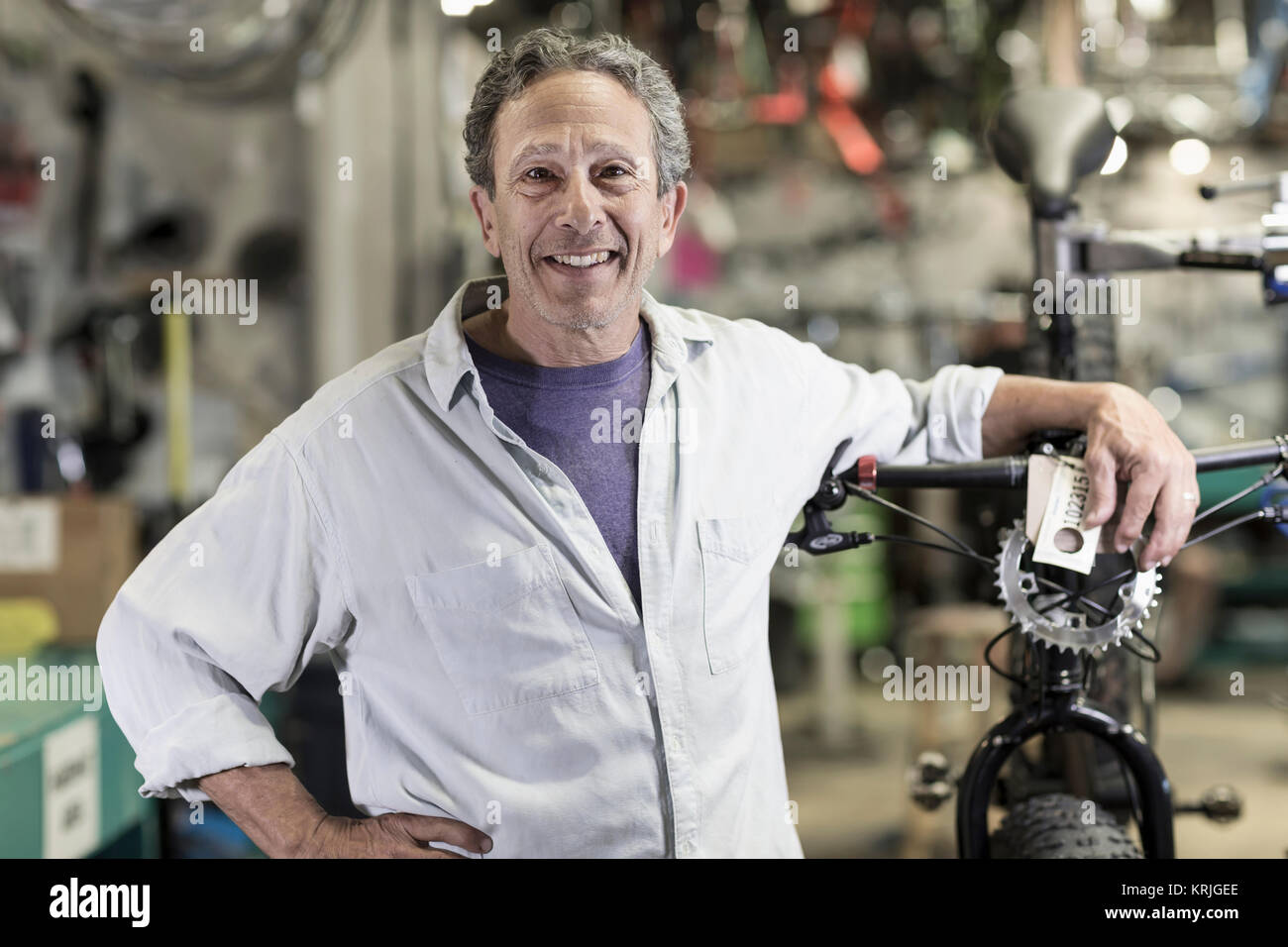 Portrait of smiling Caucasian man leaning on bicycle in shop Stock Photo