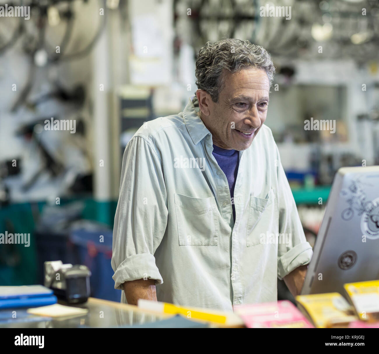Smiling Caucasian man using computer in bicycle shop Stock Photo