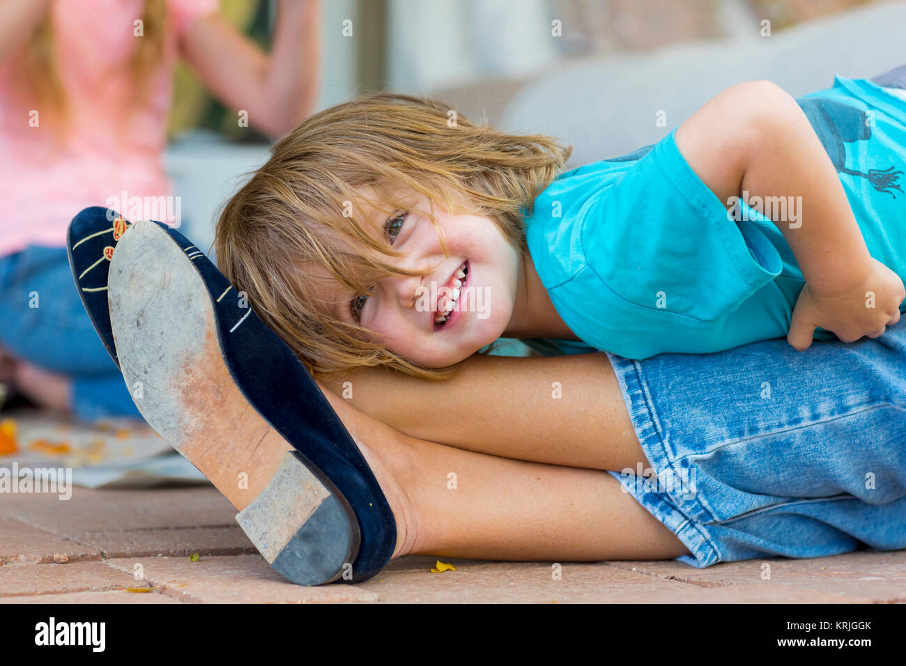 Smiling Caucasian boy laying on legs of mother Stock Photo
