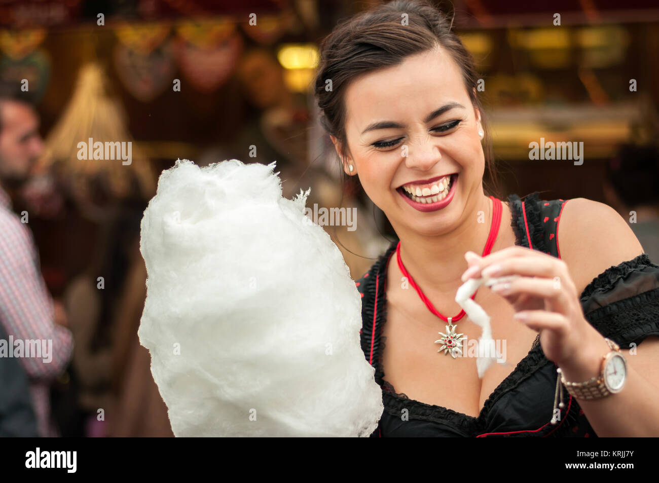 Attractive young woman wearing a traditional Dirndl dress with cotton candy floss at the Oktoberfest. Stock Photo