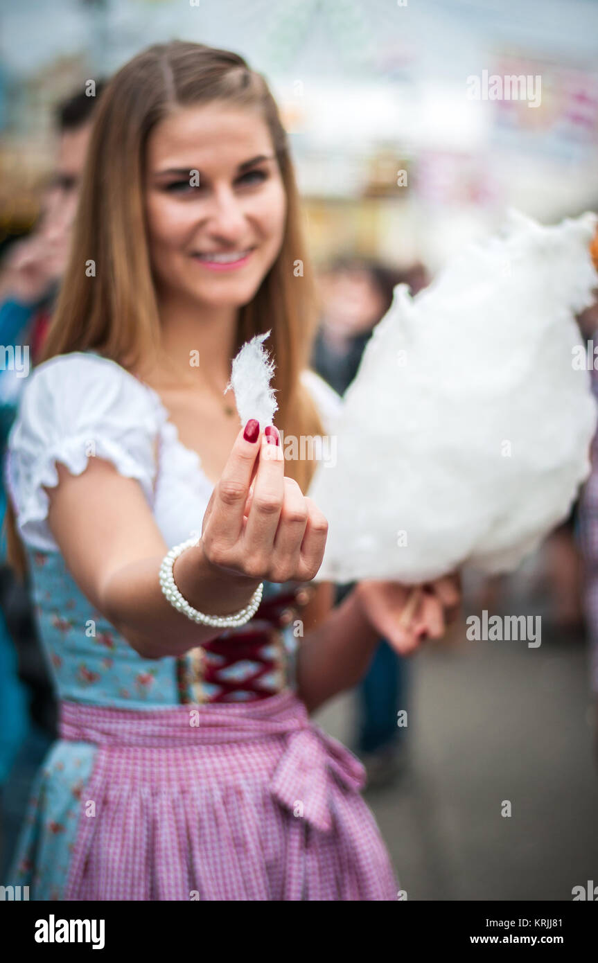Attractive young woman wearing a traditional Dirndl dress with cotton candy floss at the Oktoberfest. Stock Photo