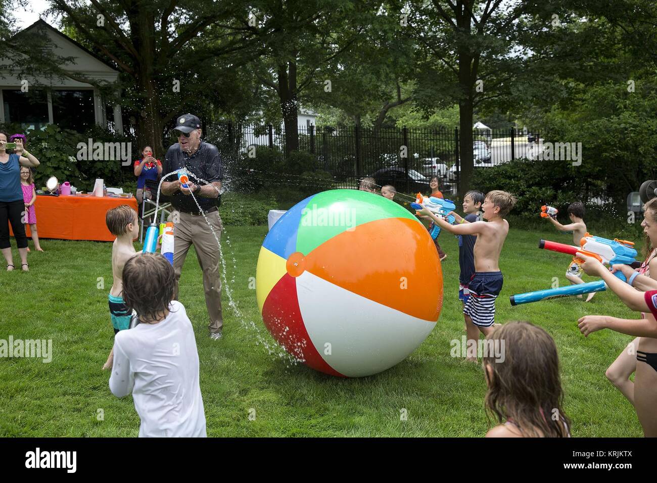 U.S. Vice President Joe Biden chases children with a super soaker water gun during the Biden Beach Boardwalk Bash at the Naval Observatory Residence June 4, 2016 in Washington, DC. Stock Photo