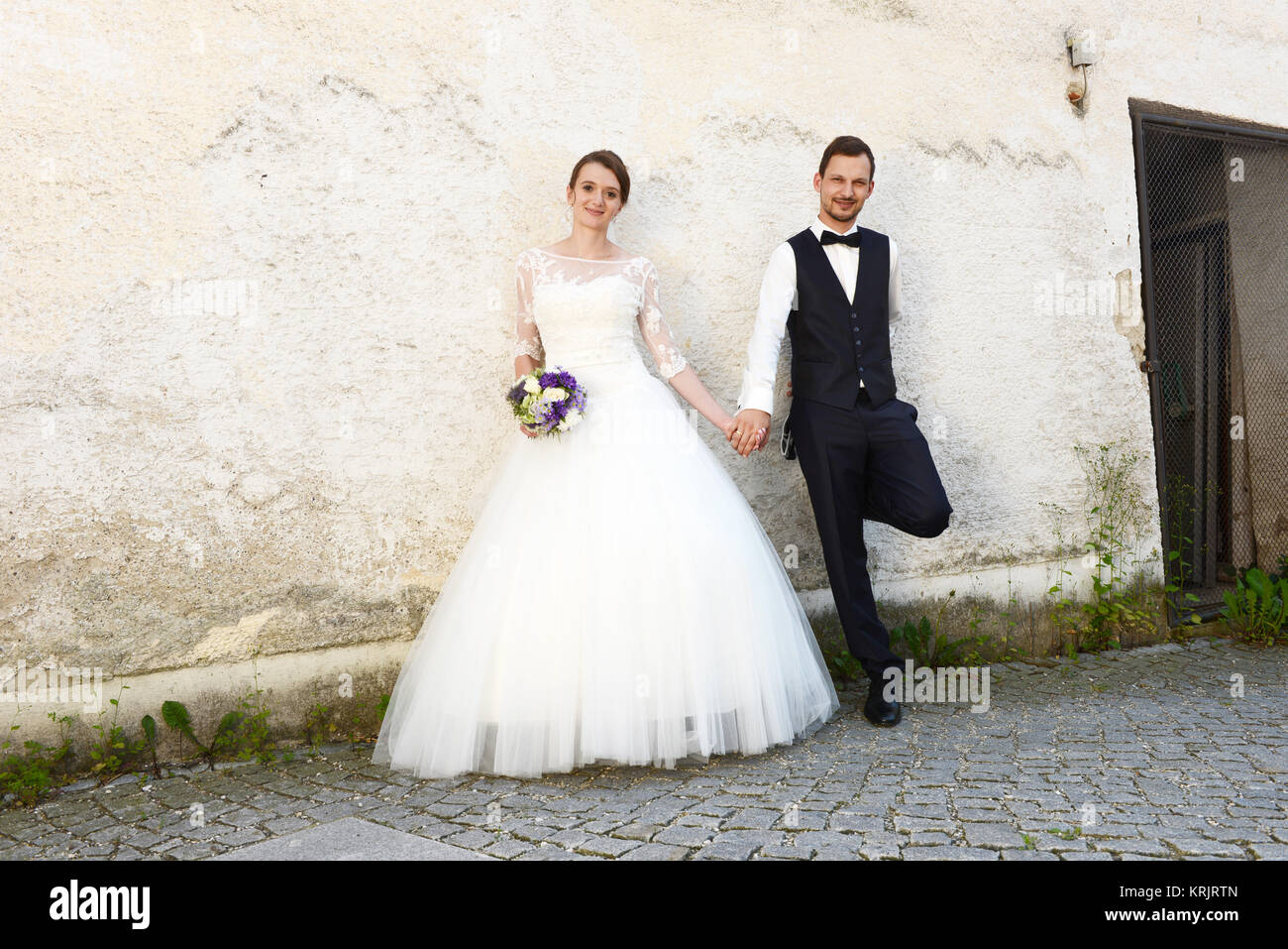 happy young bride and groom in front of an old house wall Stock Photo ...
