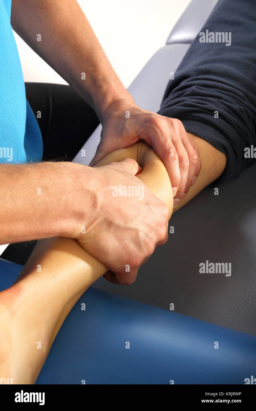 calf massage,masseur oppresses the muscle. Stock Photo