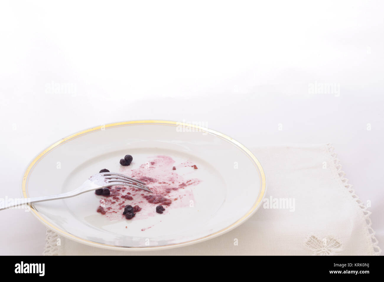 dish with leftover of a cake with bluberries and fork, on white background Stock Photo