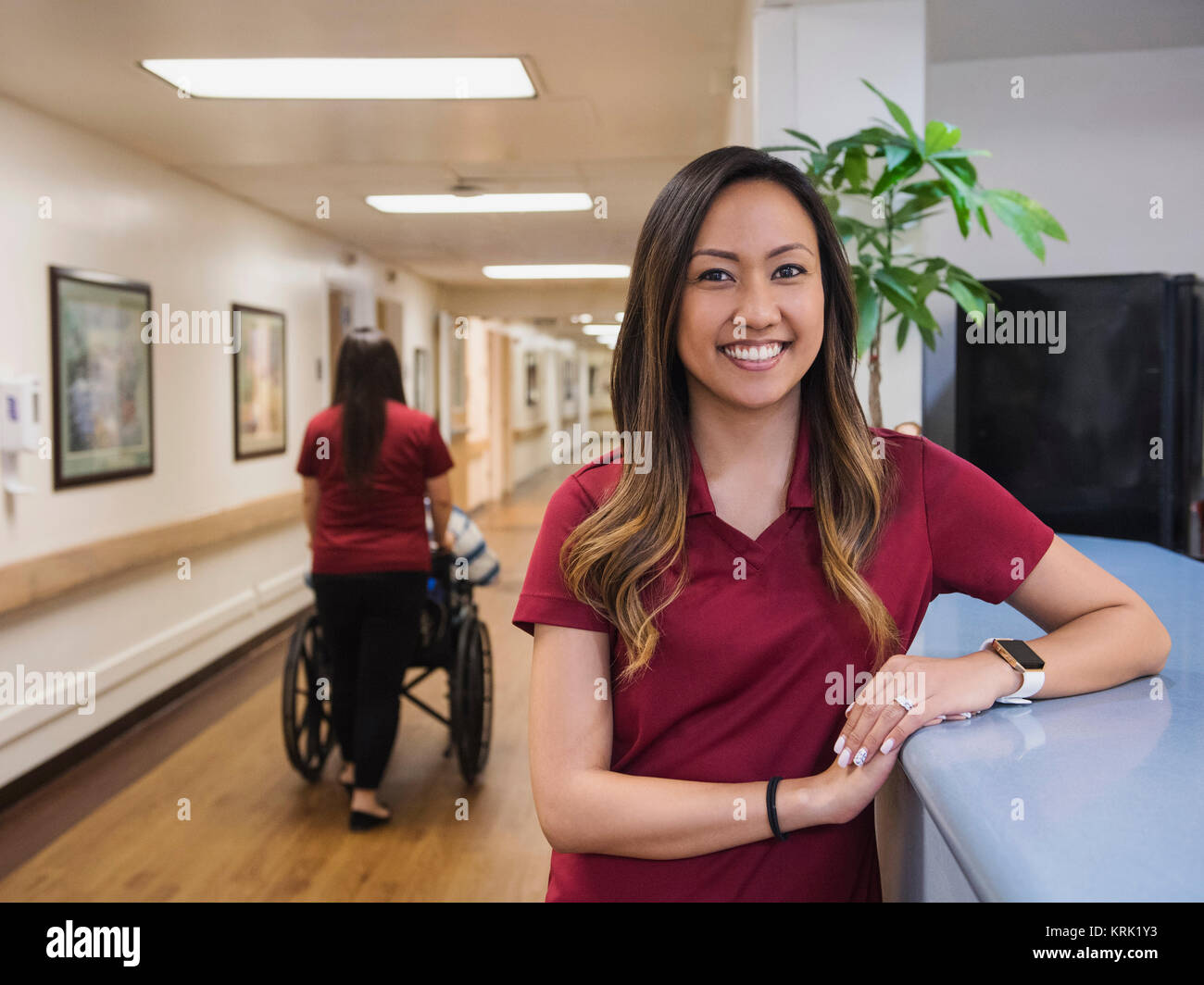 Portrait of smiling nurse leaning on counter in hospital Stock Photo