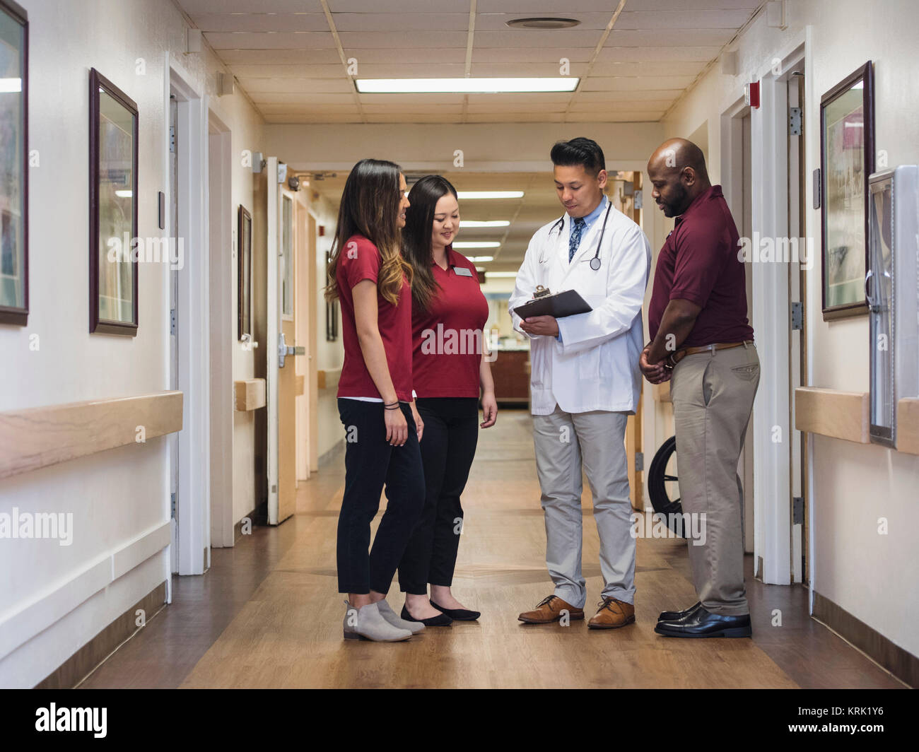 Doctor And Nurses Reading Clipboard In Hospital Corridor Stock Photo