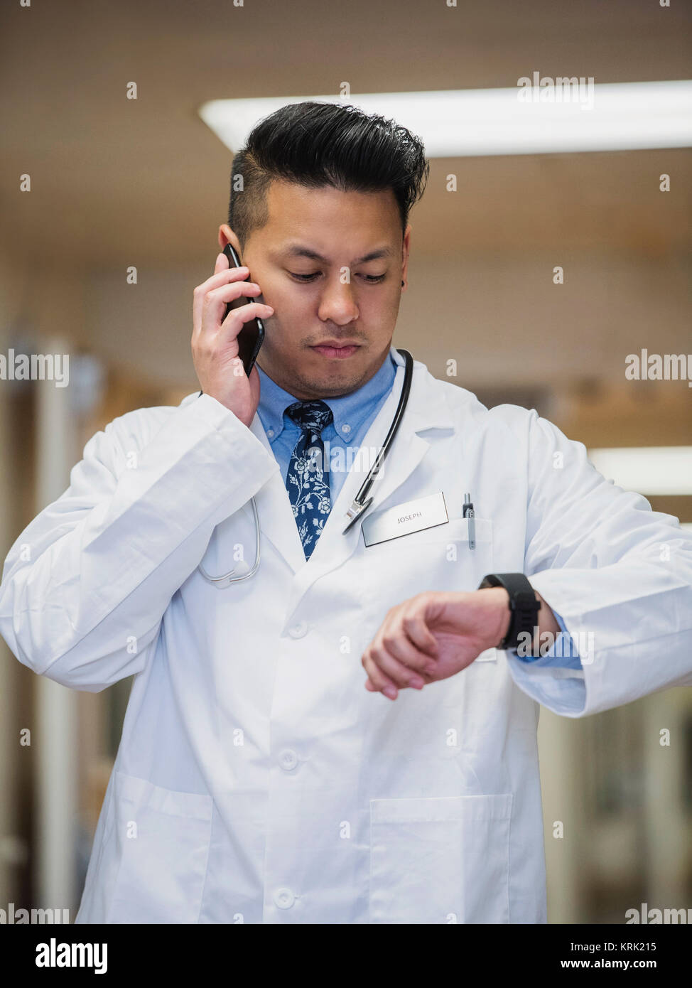 Filipino doctor talking on cell phone and checking the time Stock Photo