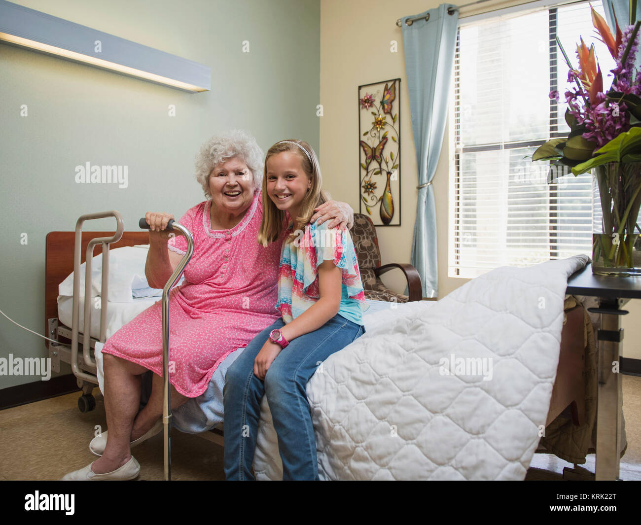 Smiling Caucasian woman sitting on bed with granddaughter Stock Photo