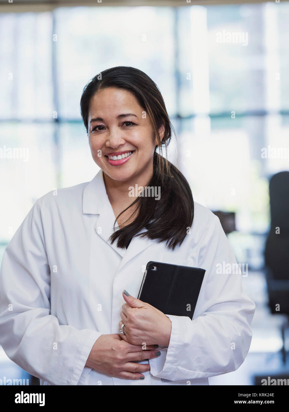 Portrait of smiling Asian physical therapist holding digital tablet Stock Photo