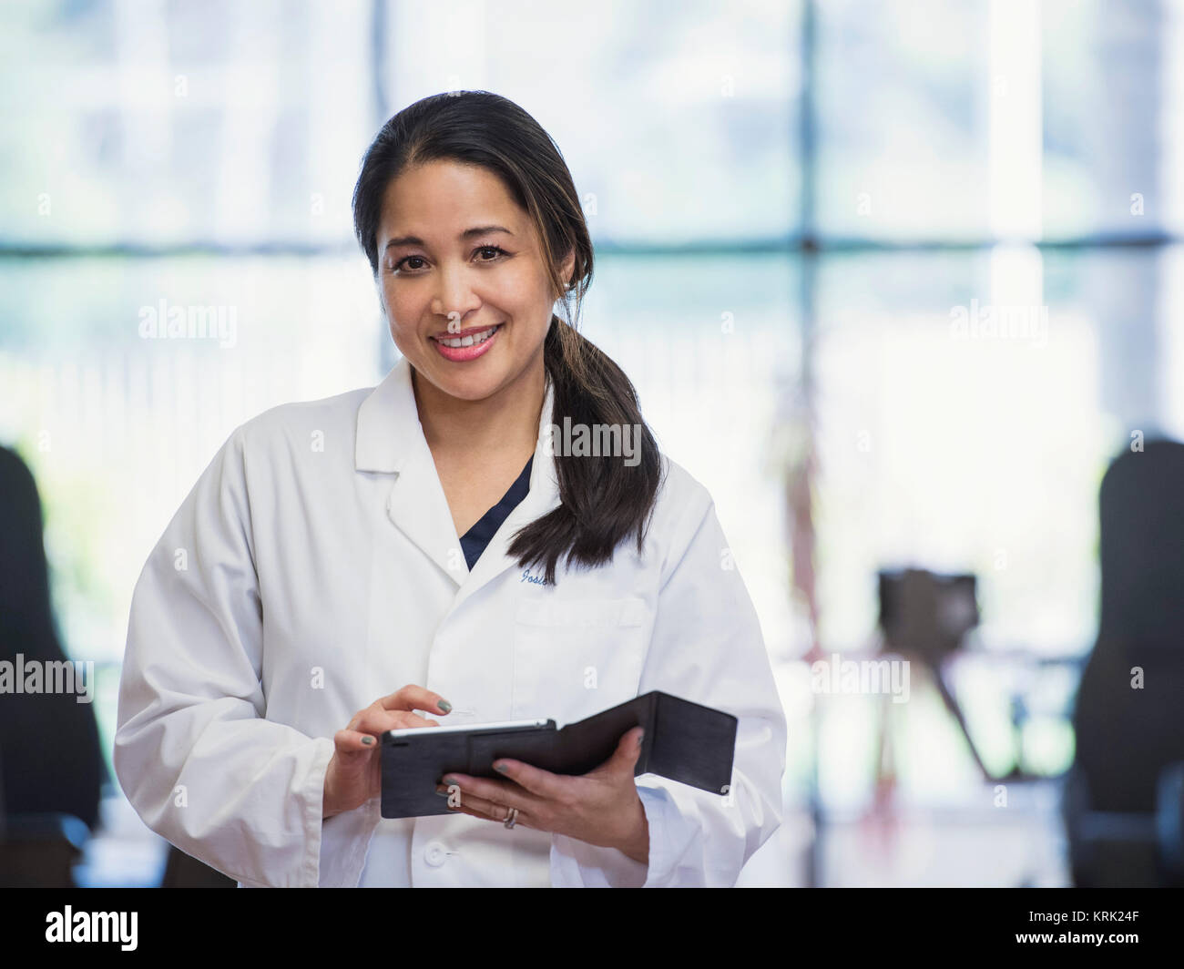 Portrait of smiling Asian physical therapist using digital tablet Stock Photo