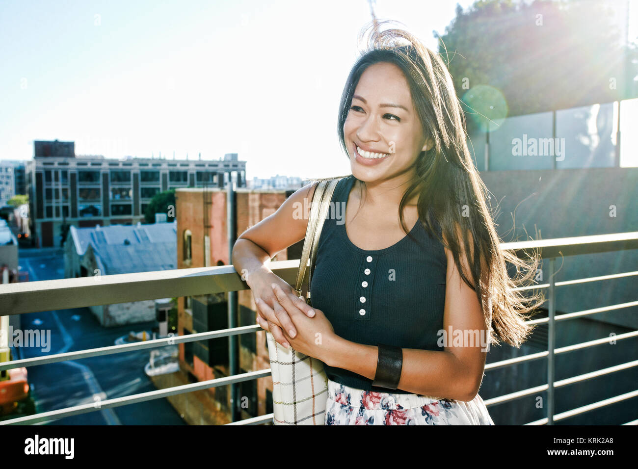 Smiling Asian woman leaning on rooftop Stock Photo