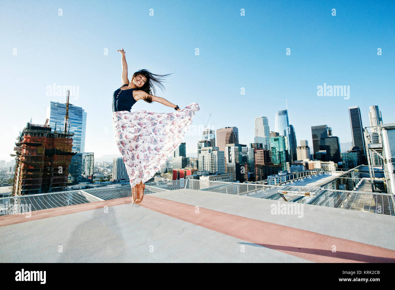 Asian woman jumping on urban rooftop Stock Photo
