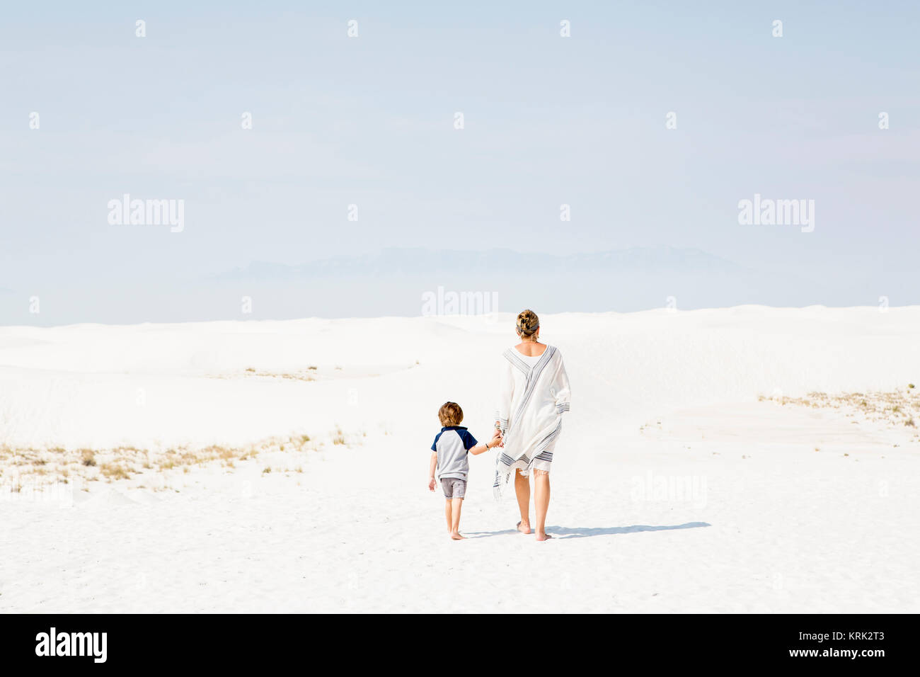 Caucasian mother and son walking in sand Stock Photo
