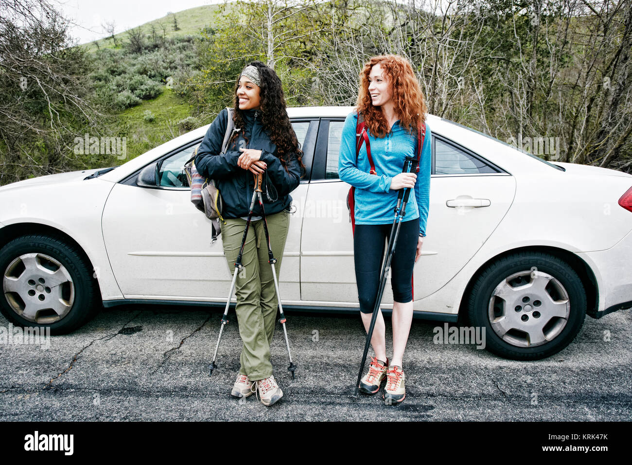 Smiling women standing near car hold and walking sticks Stock Photo