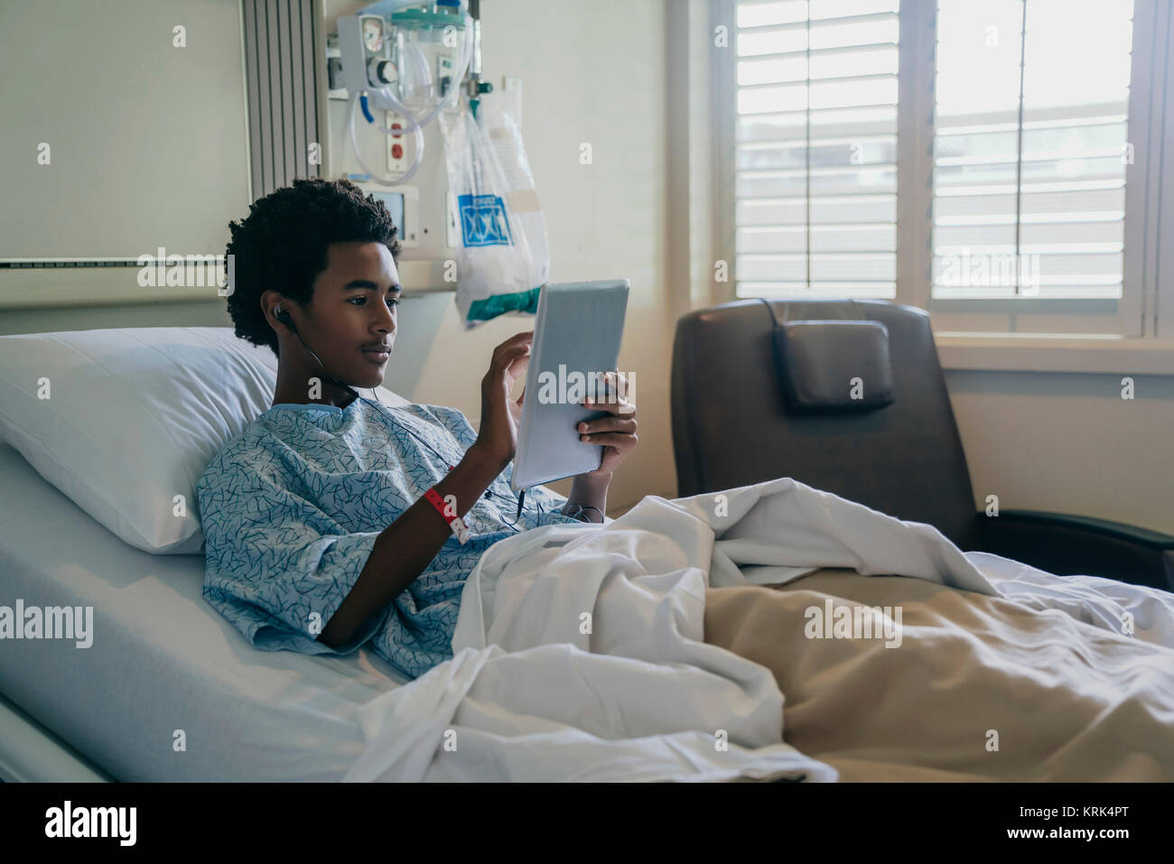 Black boy in hospital bed listening to digital tablet Stock Photo