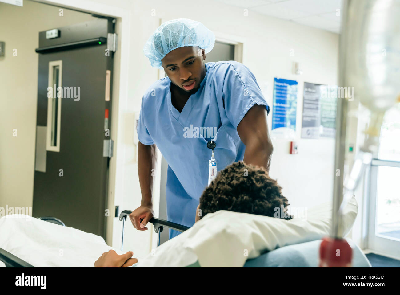 Black nurse talking to boy in hospital bed Stock Photo