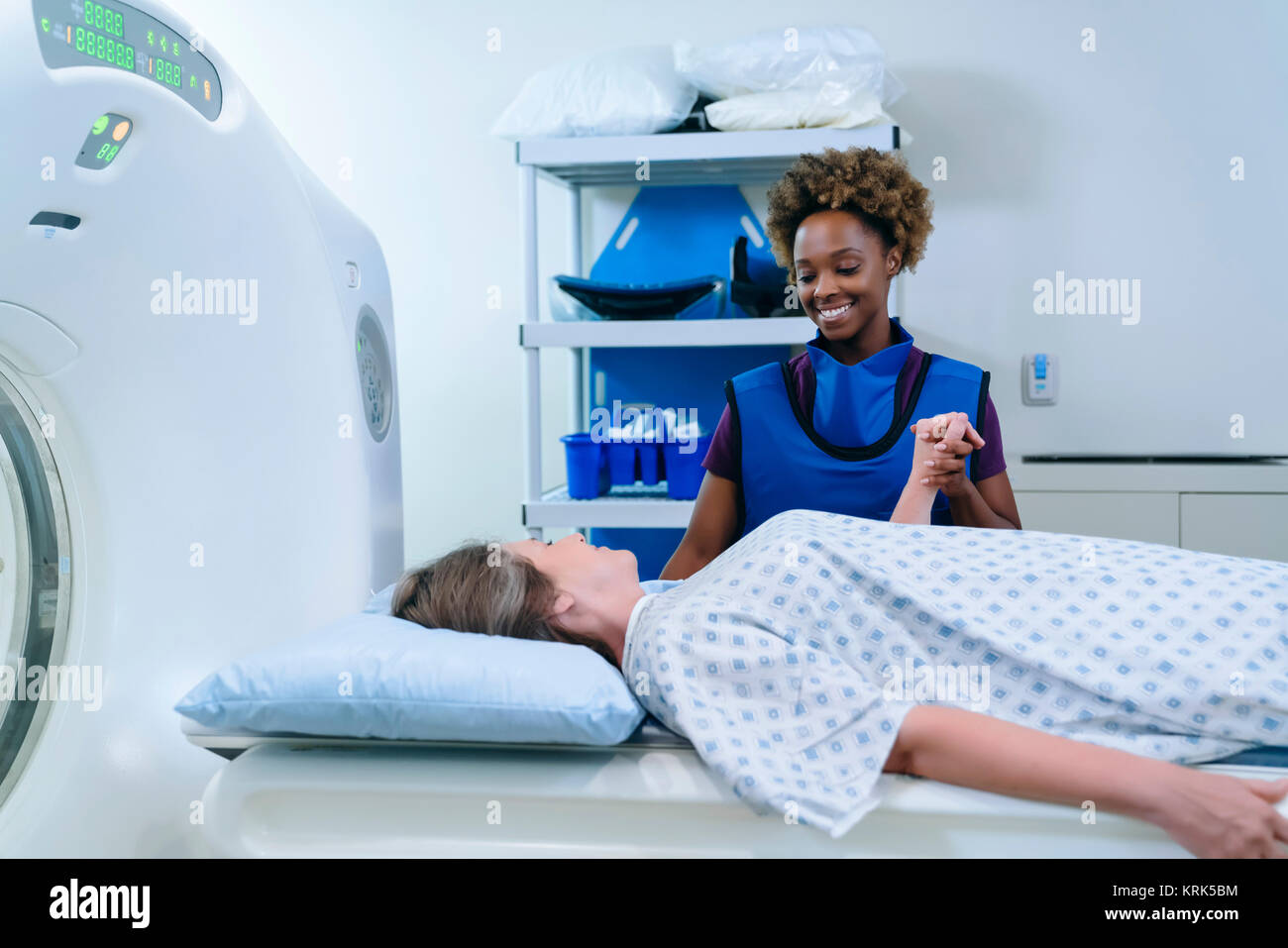 Technician holding hand of patient at scanner Stock Photo