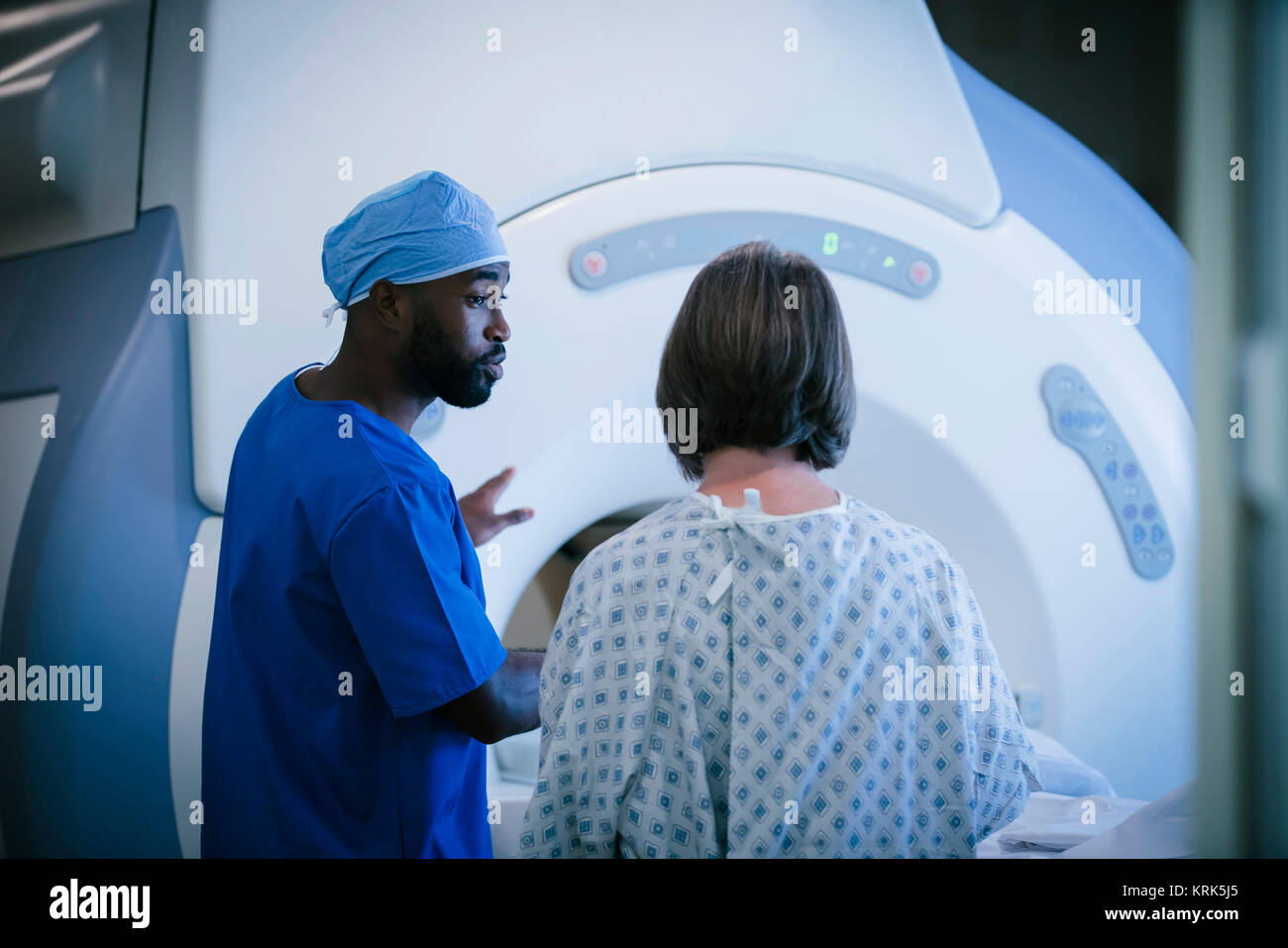 Technician talking to patient at scanner Stock Photo