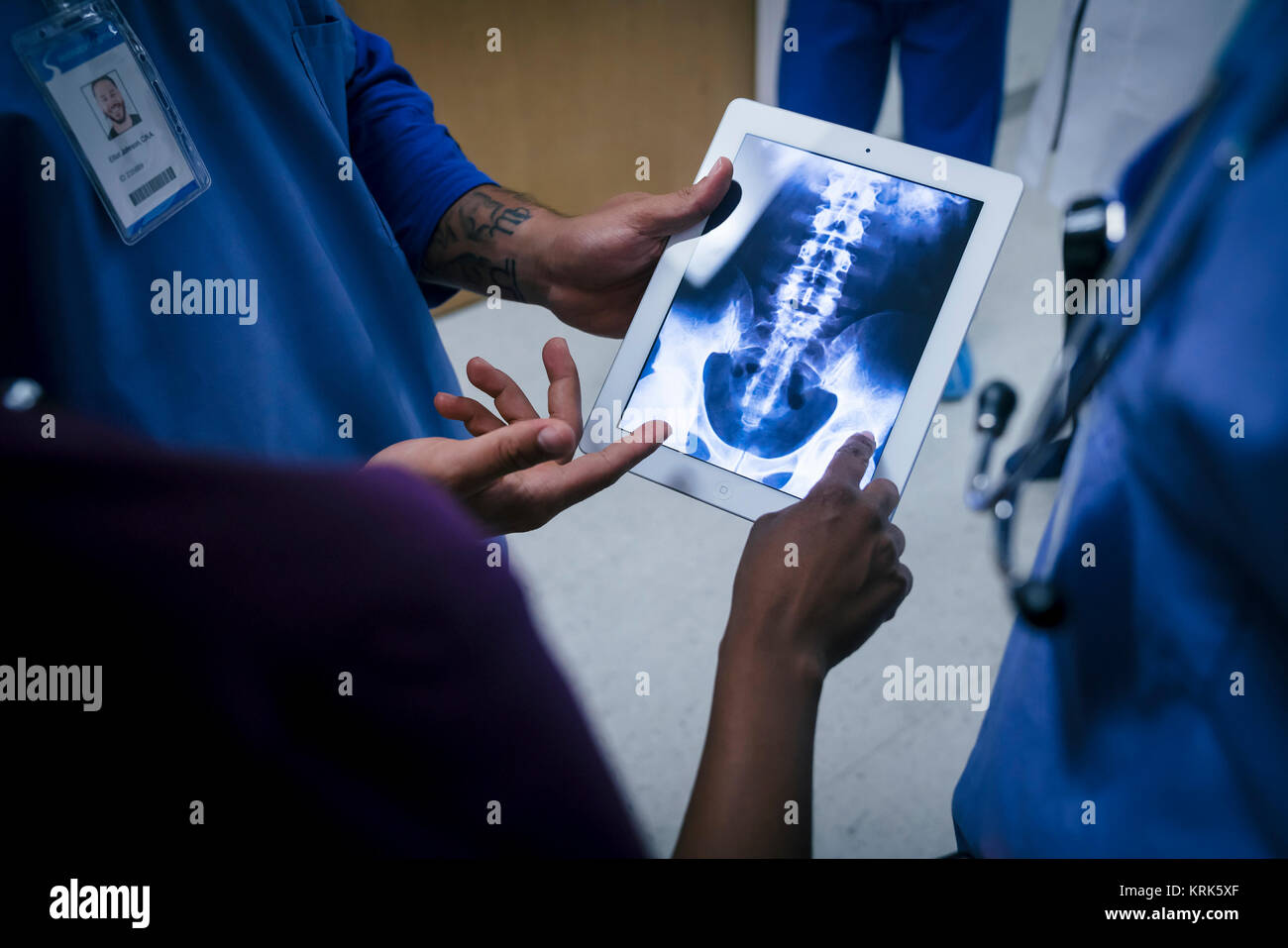 Doctors examining x-ray of pelvis and spine on digital tablet Stock Photo