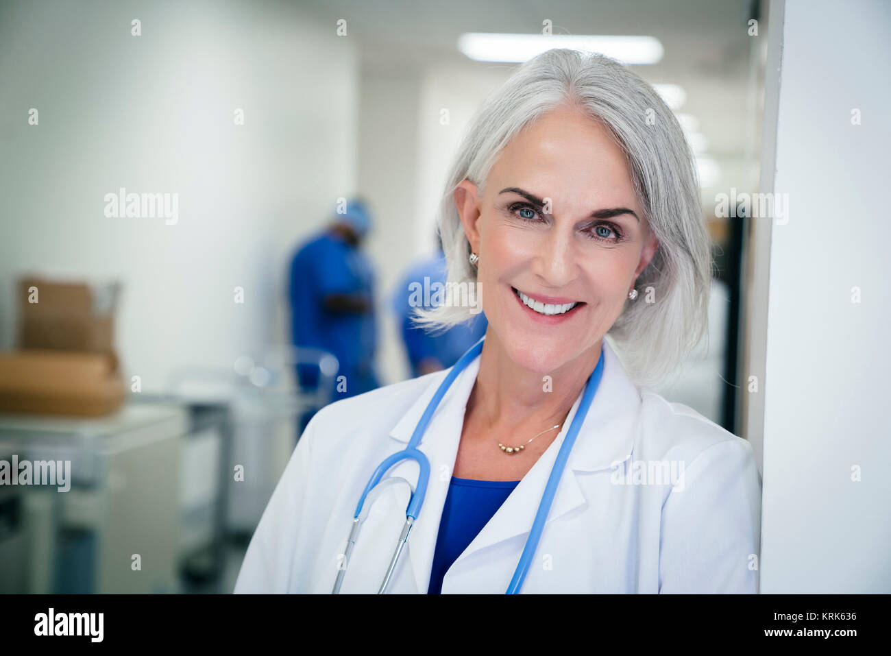 Portrait of Caucasian doctor leaning on wall in hospital Stock Photo