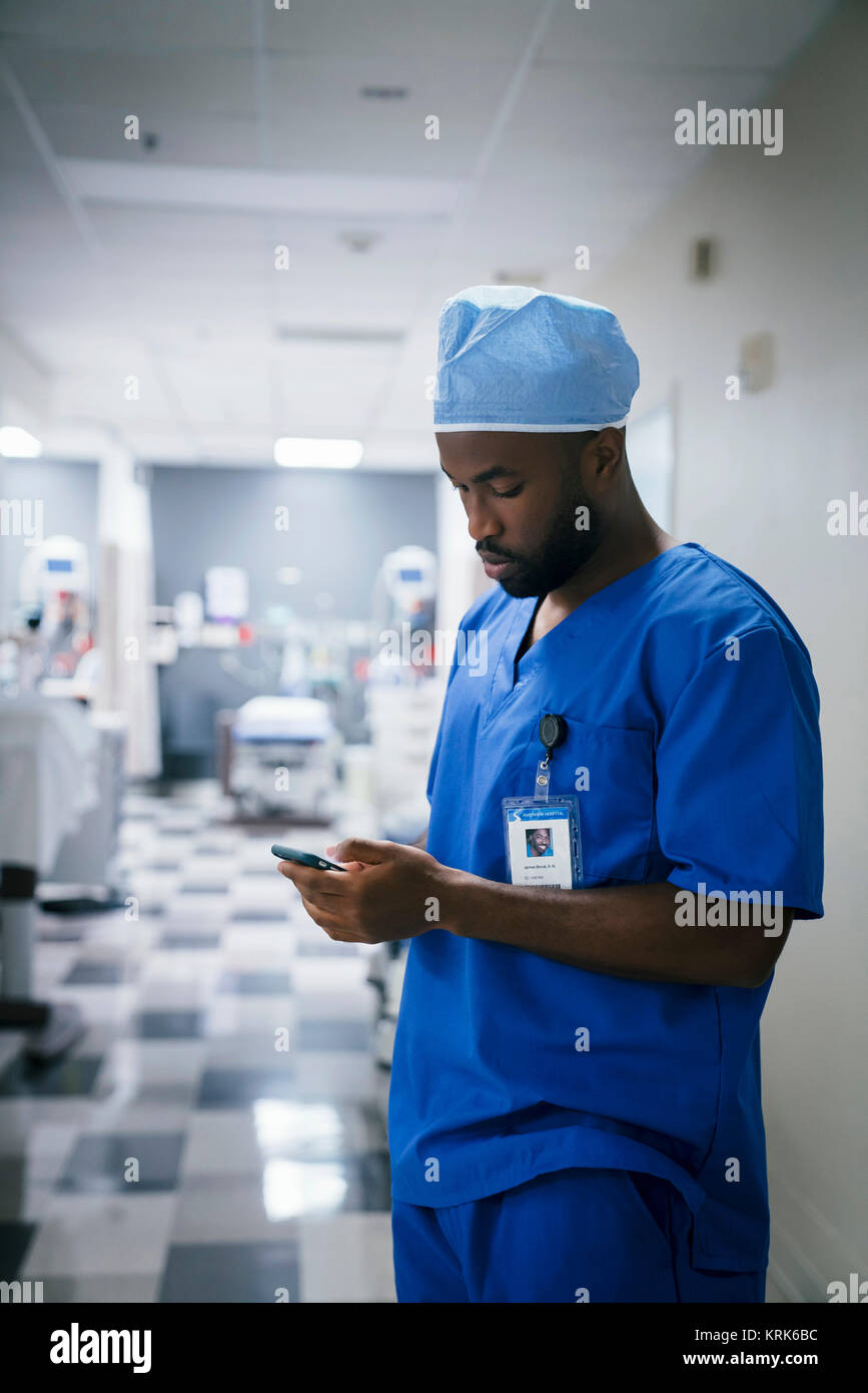 Black nurse texting on cell phone in hospital Stock Photo