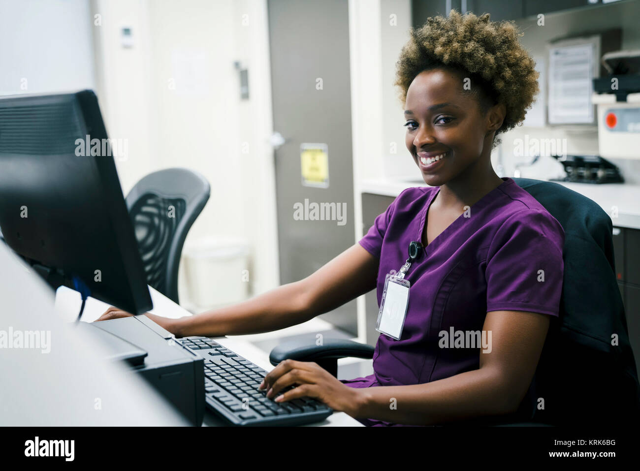 Portrait of smiling black nurse using computer Stock Photo
