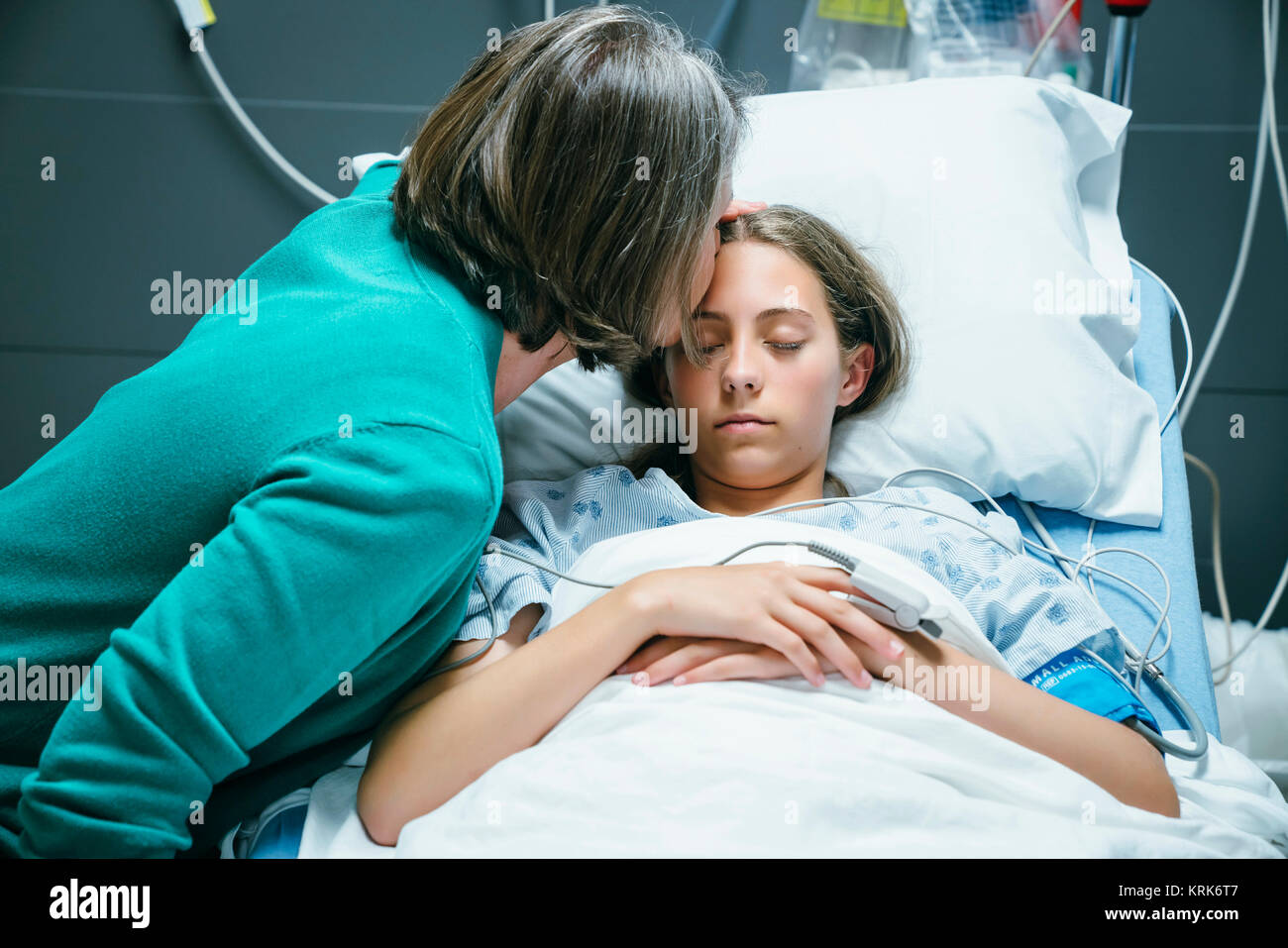 Caucasian mother kissing your daughter on forehead in hospital Stock Photo