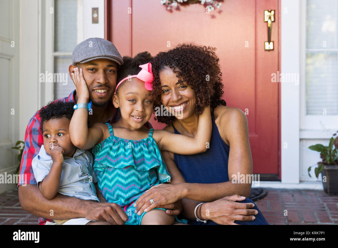 Portrait of smiling mixed race family sitting on front stoop Stock Photo