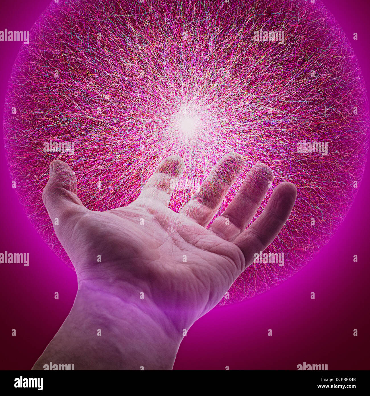 Hand of Caucasian man holding glowing sphere of purple energy Stock Photo