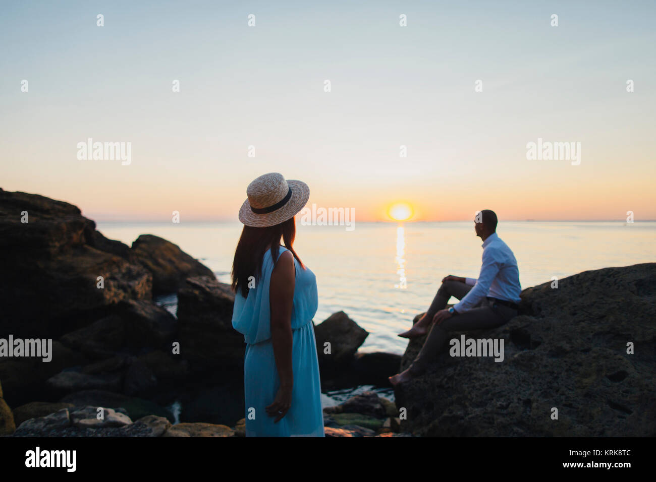 Caucasian couple admiring scenic view of ocean sunset Stock Photo