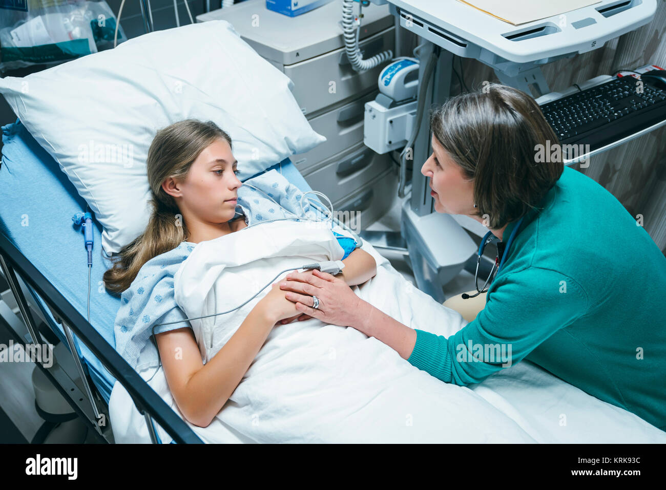 Doctor comforting Caucasian girl laying in hospital bed Stock Photo