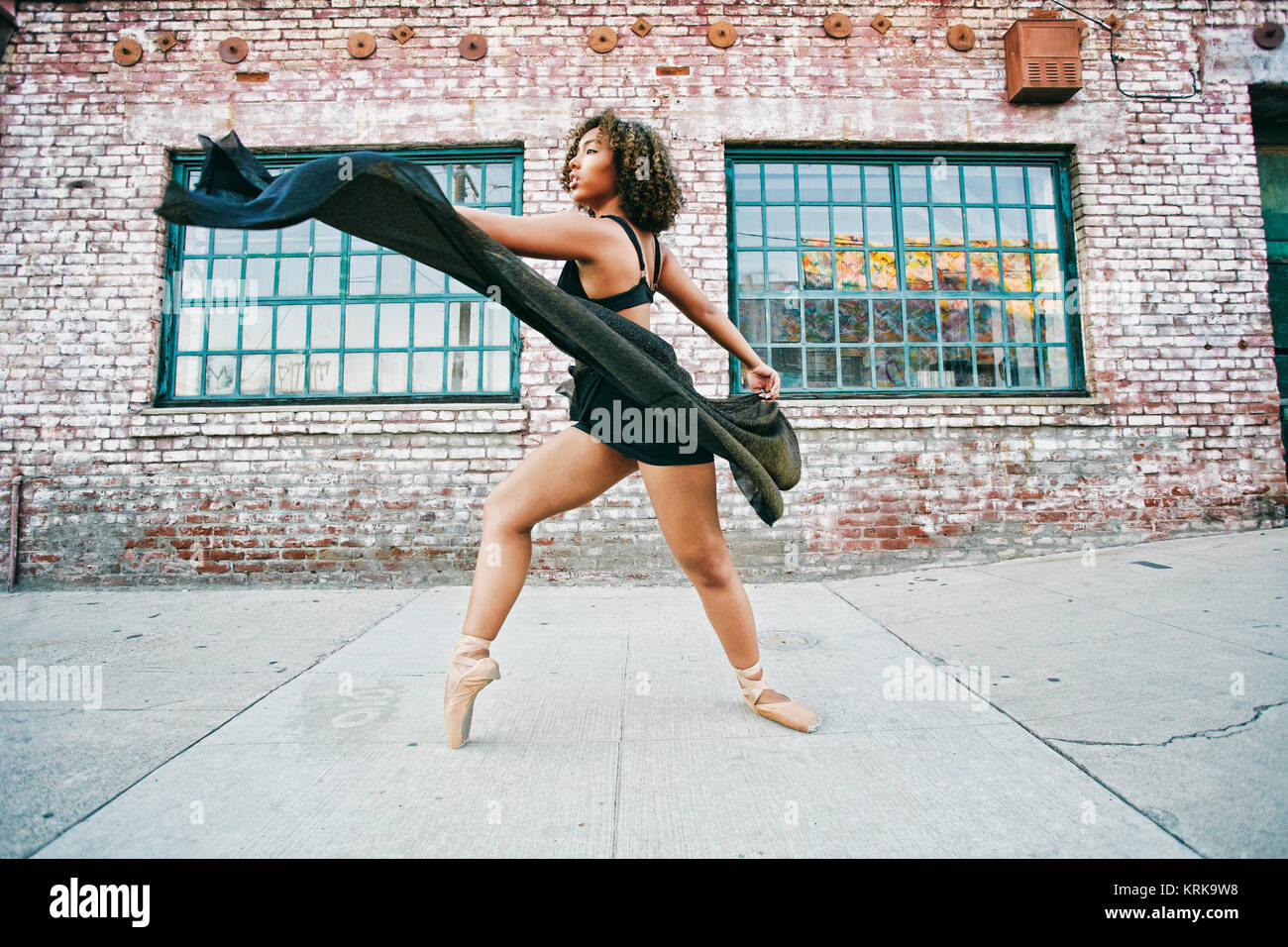 Mixed race woman dancing ballet on sidewalk Stock Photo