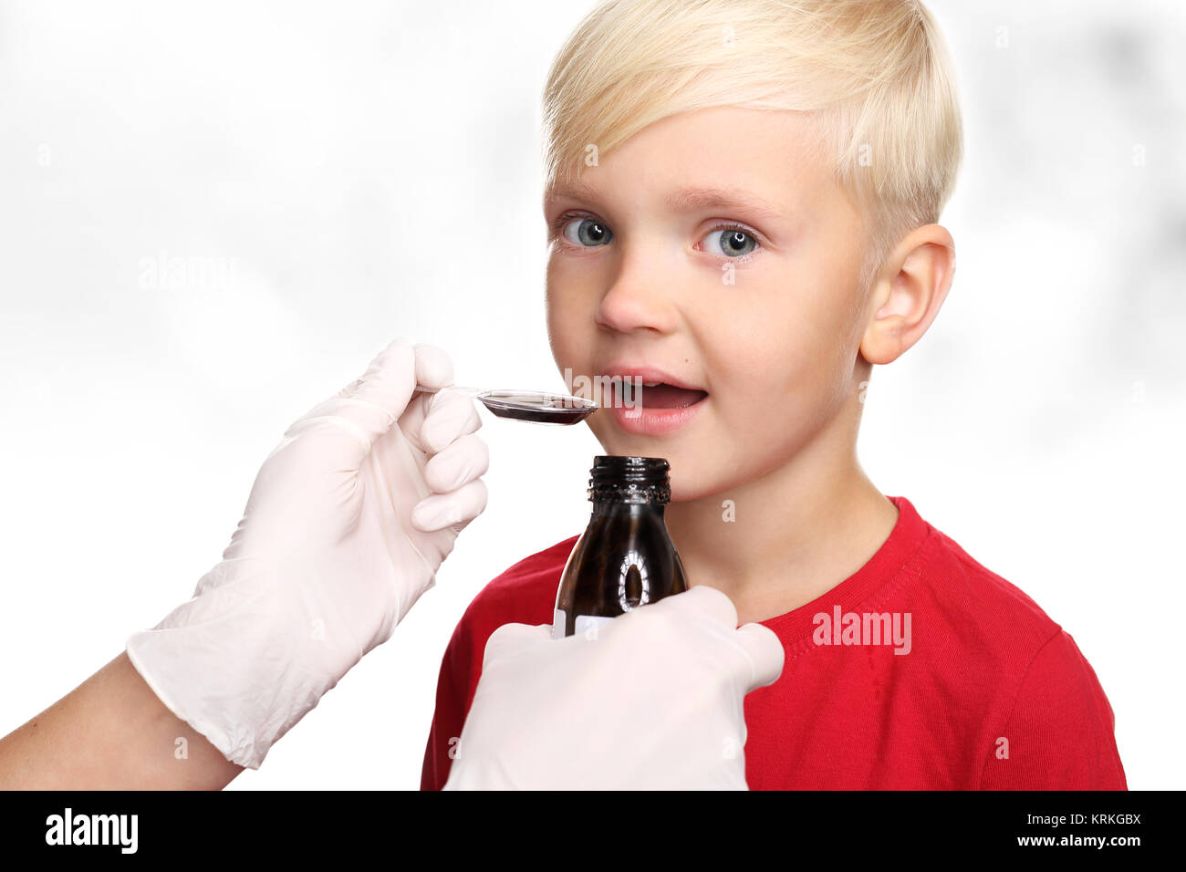 the child takes the medicine served on a spoon. Stock Photo