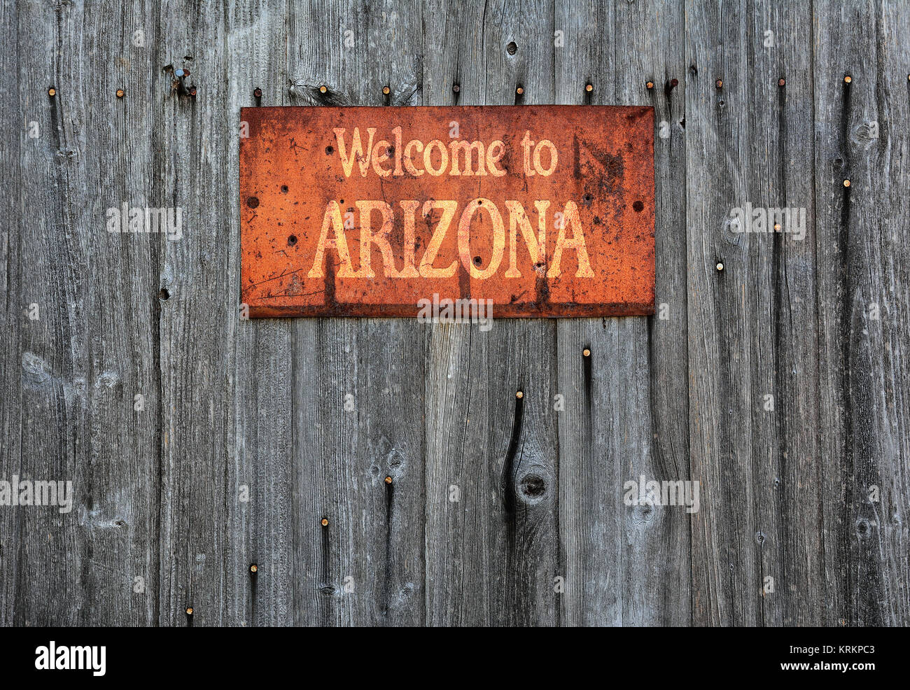 Rusty metal sign on wooden wall with the phrase: Welcome to Arizona. Stock Photo