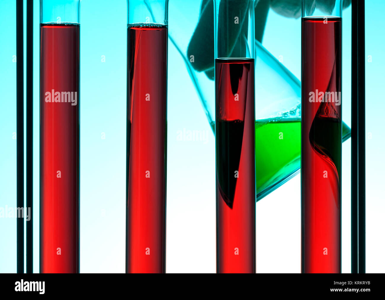 Chemistry concept. Test tubes with red liquid, hand holding beaker with ...