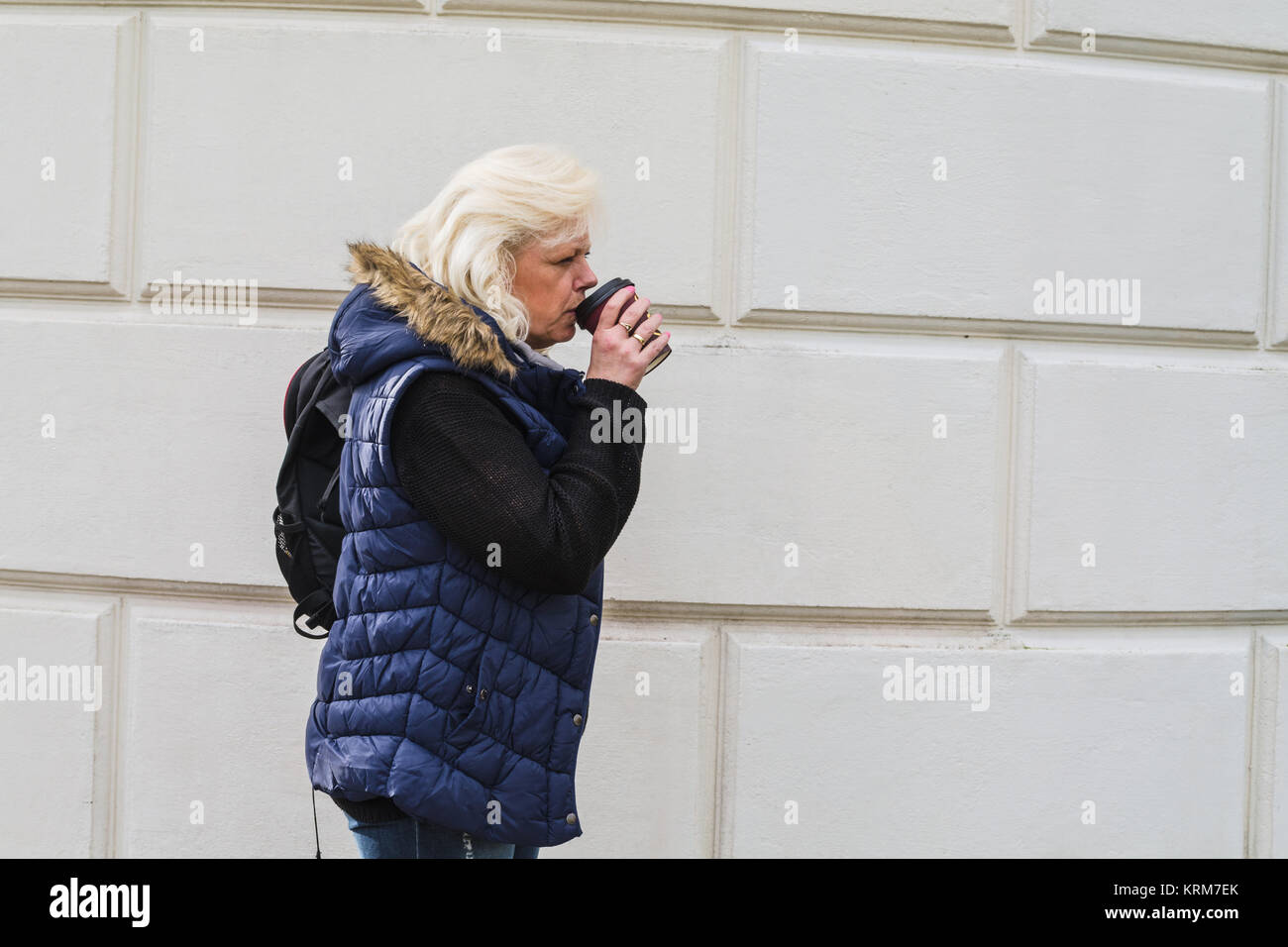 Seitenporträt einer blonden Frau mit einem Kaffee to go. Stock Photo