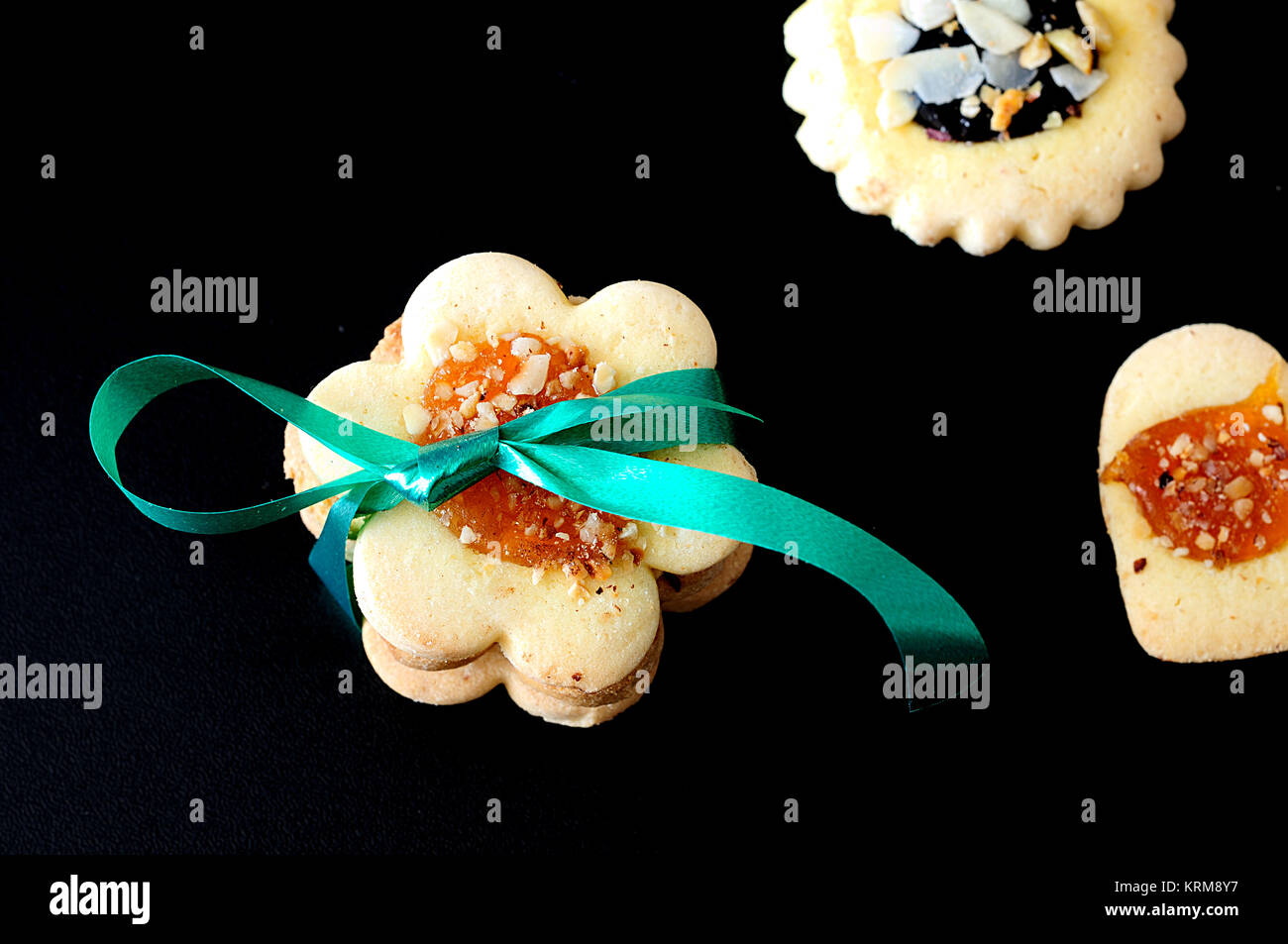 Shortbread biscuits, taken from above, selective focus on the cookies tied with green ribbon on black background, close up Stock Photo