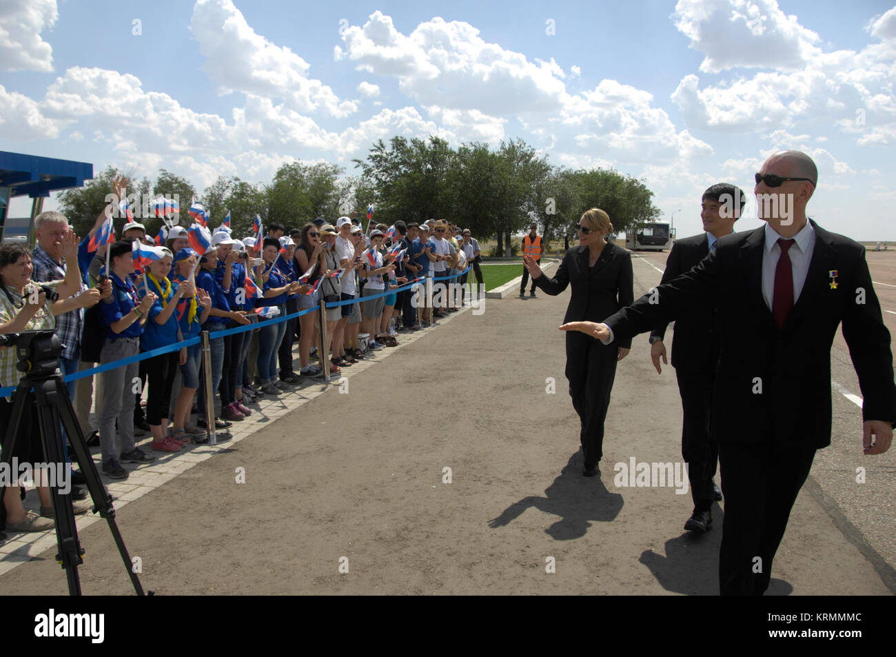 ISS Expedition 48-49 prime crewmembers Kate Rubins of NASA (left), Takuya Onishi of the Japan Aerospace Exploration Agency (center) and Anatoly Ivanishin of Roscosmos (right) wave to schoolchildren after arriving in Baikonur, Kazakhstan June 24 for final pre-launch training following a flight from Star City, Russia. The trio will launch July 7 from the Baikonur Cosmodrome in Kazakhstan on the Soyuz MS-01 spacecraft for a planned four-month mission on the International Space Station.  NASA/Alexander Vysotsky Soyuz MS-01 crew members wave to schoolchildren after arriving in Baikonur Stock Photo