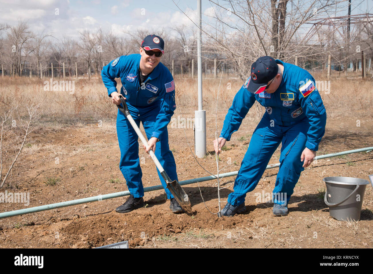 At the Cosmonaut Hotel crew quarters in Baikonur, Kazakhstan, Expedition 51 crewmember Fyodor Yurchikhin of the Russian Federal Space Agency (Roscosmos, right) helps crewmate Jack Fischer of NASA (left) plant a tree in Fischer’s name April 13 as part of traditional pre-launch activities. Fischer and Yurchikhin will liftoff April 20 from the Baikonur Cosmodrome on the Soyuz MS-04 spacecraft for a four and a half month mission on the International Space Station.  NASA/Victor Zelentsov Soyuz MS-04 crew during the tree planting ceremony Stock Photo