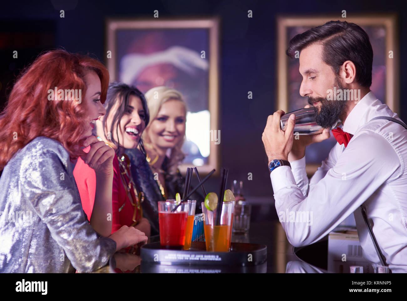 Bartender and attractive women at bar counter Stock Photo