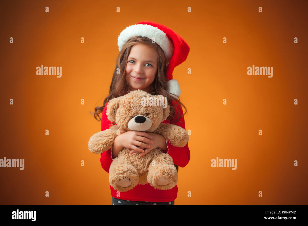 The cute cheerful little girl on orange background Stock Photo