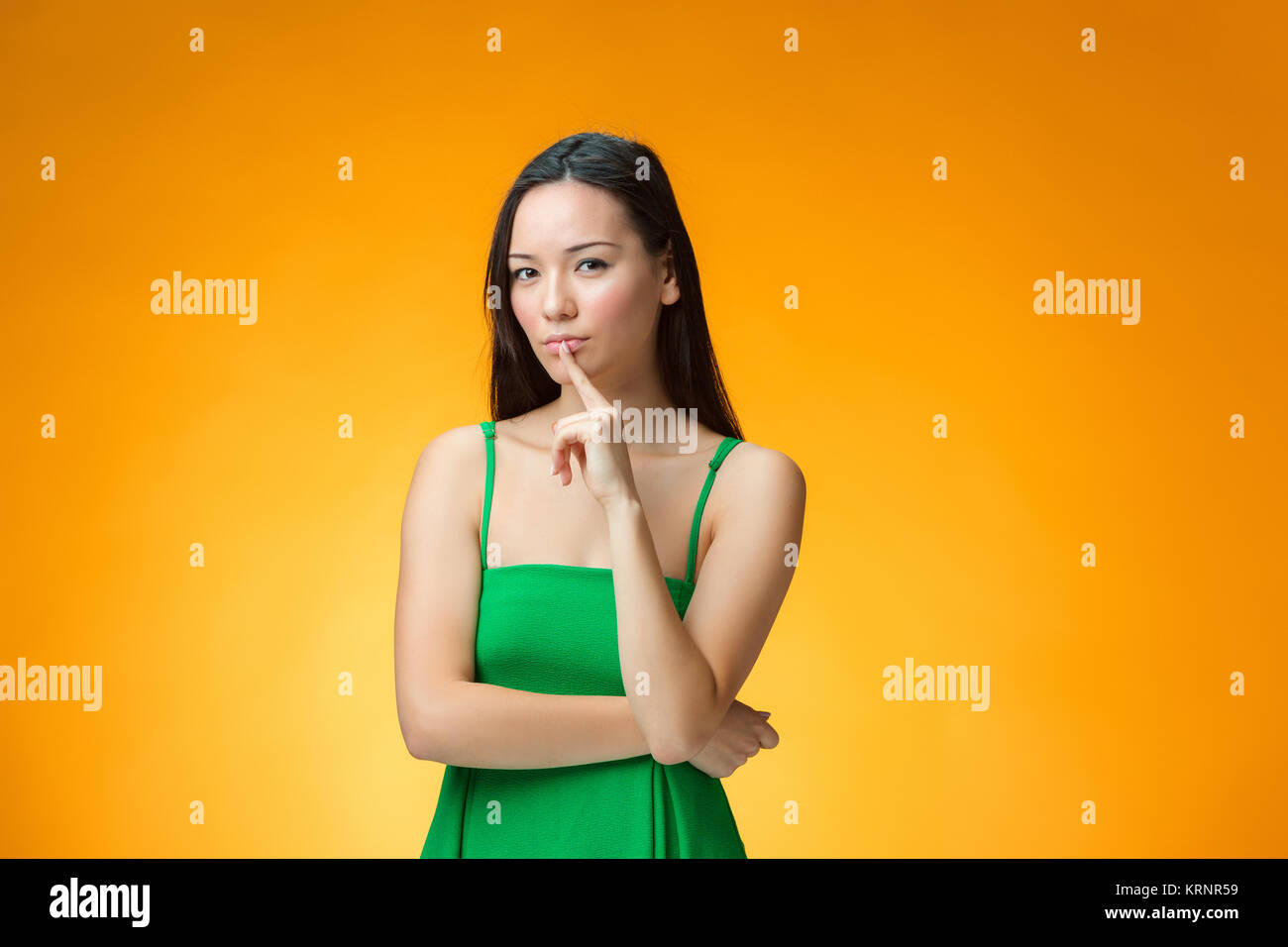 The thinking Chinese girl on yellow background Stock Photo