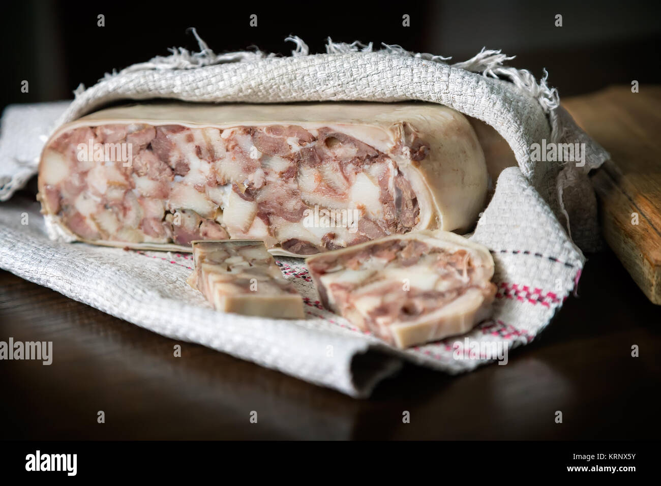 On the table wrapped in a napkin, sliced pork stomach, stuffed with meat and fat. Presented on a dark background. Stock Photo